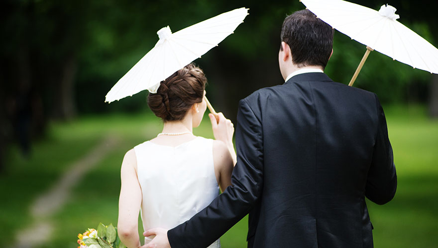 Braut und Bräutigam gehen von uns weg. Sie haben beide einen chinesischen Sonnenschirm aus China.