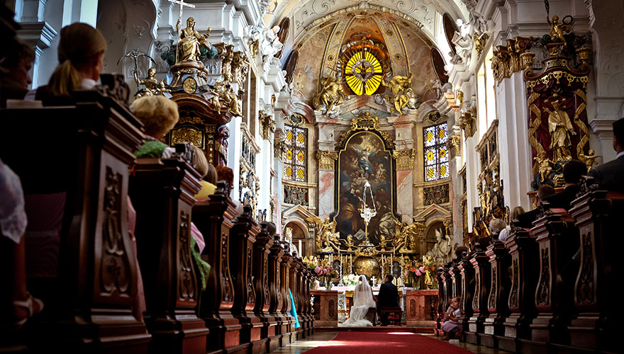 Die Kirche in Dürnstein bietet hier ein schönes Ambiente für eine Trauung. Zwischen den voll besetzten Kirchenbänken sitzt ein kleines Mädchen. 